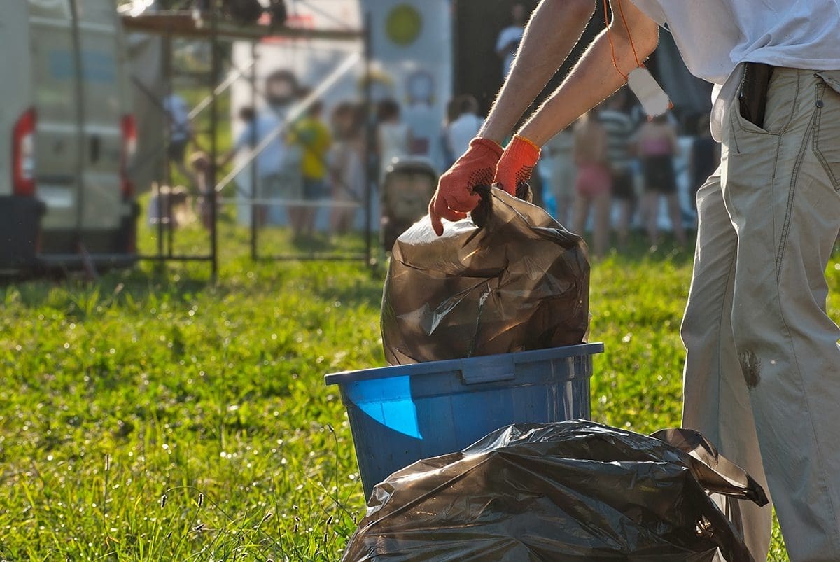 A person taking trash out of a can at an event.